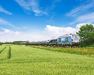 Der blaue AUTOZUG Sylt fährt durch die Felder Nordfrieslands